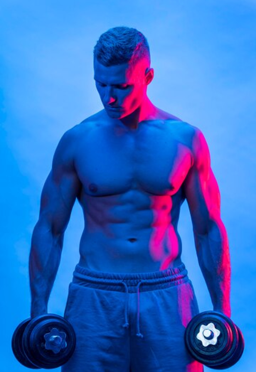 Спортивная мужчина держит в руках гантели